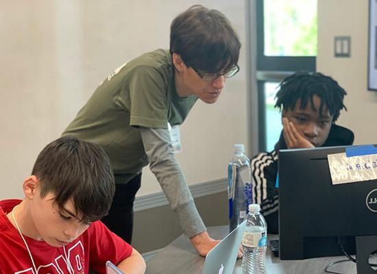 A 在线博彩 professor helps kids on laptops